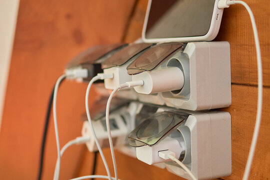 Overloaded power outlet with charging devices on wall, showing electrical risks