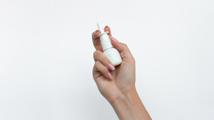 Women's hand holding a white bottle with nasal spray isolated on a white background