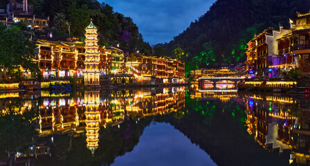 Chinese tourist attraction destination - Feng Huang Ancient Town (Phoenix Ancient Town) on Tuo Jiang River illuminated at night. Hunan Province, China