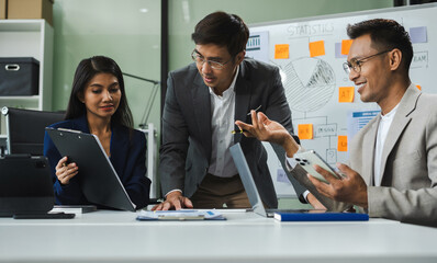 Asian businessman showing hand and smiling young team of colleagues making good business discussion in modern coworking office concept teamwork people.