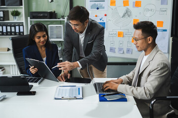 Asian businessman showing hand and smiling young team of colleagues making good business discussion in modern coworking office concept teamwork people.