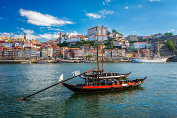 View of Porto city and Douro river with traditional boats with port wine barrels and sailing ship from famous tourist viewpoint Marginal de Gaia riverfront. Porto, Vila Nova de Gaia, Portugal