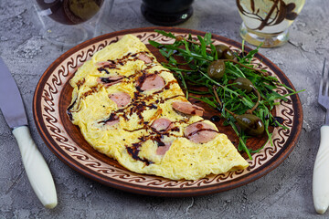 Fried omelet stuffed with sausage. Omelette with arugula and capers