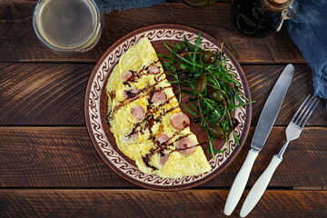 Fried omelet stuffed with sausage. Omelette with arugula and capers