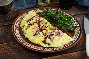 Fried omelet stuffed with sausage. Omelette with arugula and capers