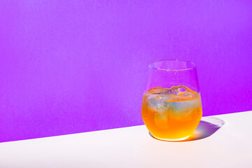 Orange alcoholic cocktail drink with gin, lemon juice and honey syrup, purple background