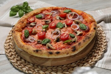 Delicious pizza with vegetables, salami, mushrooms and basil on wooden table, closeup