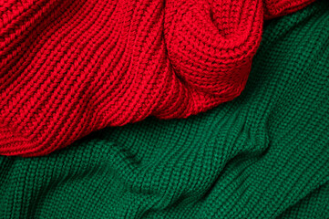Red and green knitted sweater top view. Texture of woolen cotton winter autumn cozy sweater, clothes. Knitted jumper, pullover, fashion