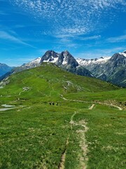 The Tour du Mont Blanc trail, TDMB, leading across lush green mountain meadow with full view of the...