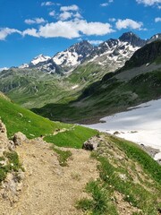 The Tour du Mont Blanc trail, TDMB, leading across lush green mountain meadow with full view of the...