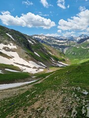 The Tour du Mont Blanc trail, TDMB, leading across lush green mountain meadow with full view of the...