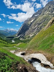  River in Val Ferret valley in Italy, with overcast sky and rocky mountain range
