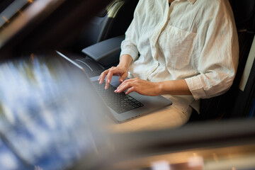 A person is working on a laptop inside a car during their commute to a destination