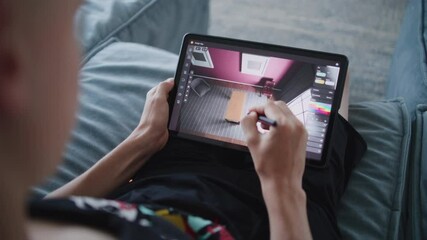 Talented teenager with digital stylus and tablet in hands sits at home, creates 3d model of room. Creative designer draws design for project using 3d modeling program. Modern technologies. Close up. - Powered by Adobe