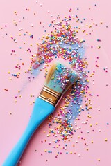 A paintbrush with pastel blue handle, covered in colorful sprinkles of different sizes and shapes