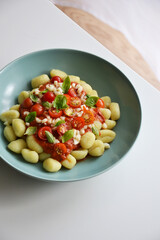 Italian gnocchi with tomato sauce with mozarella and basil on plate  on white background