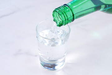韓国の伝統的な蒸留酒、よく冷えた韓国焼酎（ソジュ）をグラスに注ぐ