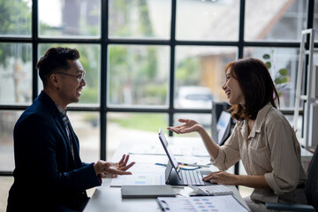 A man and a woman are talking in a room with a laptop on the table