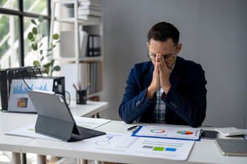 Naklejka premium A man is sitting at a desk with a laptop and a stack of papers