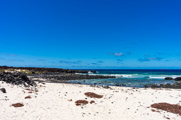 Sandstrand mit Vulkanfelsen und klarem Ozean