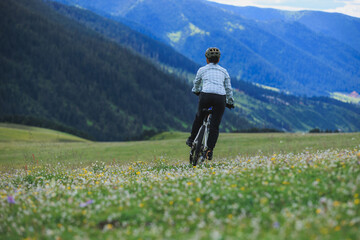 Fototapeta premium Riding mountain bike on flowering grassland mountain