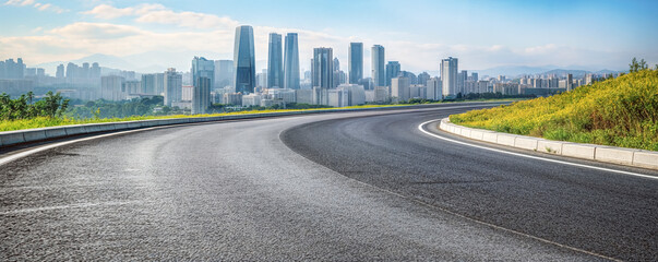 Curved asphalt road leading to a modern city skyline. Urban landscape background with copy space