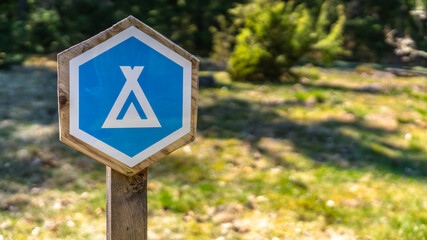 camping field with blue tent sign post in front