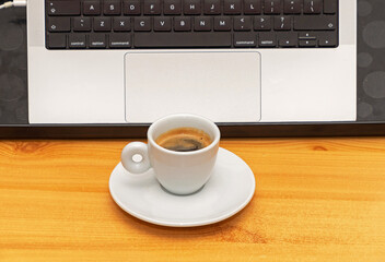 Espresso in a cup in front of open laptop