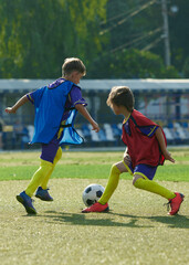 Boys, children in red and blue uniforms in motion on outdoor stadium, competing for victory,...