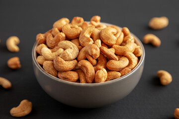 Roasted Organic Cashews in a Bowl on a black background, side view.