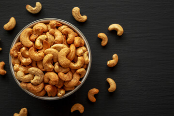 Roasted Organic Cashews in a Bowl on a black background, top view. Copy space.