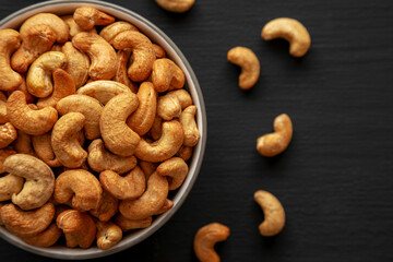 Roasted Organic Cashews in a Bowl on a black background, top view.
