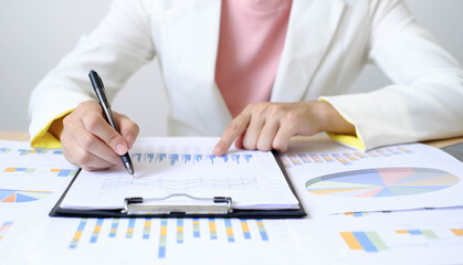 Asian businesswoman sit at their desks and calculate financial graphs showing results about their...