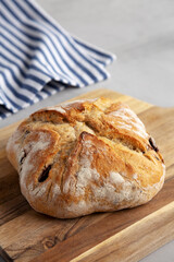 Homemade Bread with Kalamata Olives on a wooden board, side view.