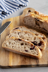 Homemade Bread with Kalamata Olives on a wooden board, side view.