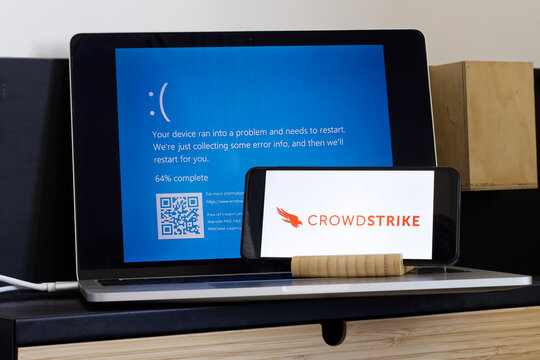 CrowdStrike logo and blue computer screen during mass tech outages worldwide have caused IT systems to shut down, Microsoft system error caused by CrowdStrike.
