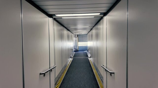 A passenger's personal perspective walking down a jet bridge to board an airplane.  	