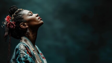 Fototapeta premium A person adorned in a detailed, traditional costume gazing upwards thoughtfully, illuminated softly against a dark backdrop, conveying a sense of introspection and grace.