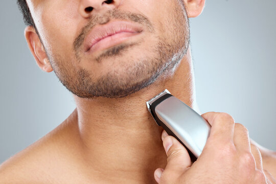 Shave, electric razor and man cutting beard hair for grooming and hygiene or health on a gray studio background. Morning, routine and equipment with model with trimmer for haircare and wellness