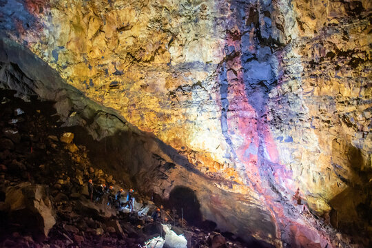 A group of tourists with flashlights exploring inside the Thr&iacute;hn&uacute;kag&iacute;gur volcano in Iceland