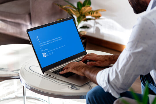 Man with laptop showing Blue screen of death or BSOD on the monitor screen. Faulty Microsoft operating system Windows 10. Rosario, Argentina - July 19, 2024.