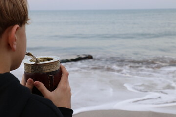 Niño tomando mates en la playa