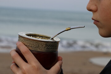 Niño tomando mates en la playa