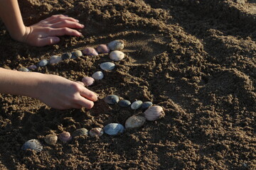 Niño escibiendo con ostras sobre la arena