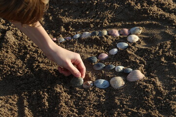 Niño escibiendo con ostras sobre la arena