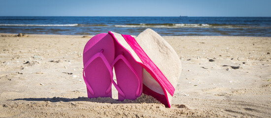Straw hat and slippers on sand at beach. Accessories for relax in summer