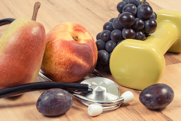 Fresh fruits, dumbbells, stethoscope. Healthy lifestyle and nutrition