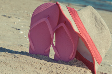 Flip flop and straw hat on beach. Accessories for relax on sand. Summer vacation