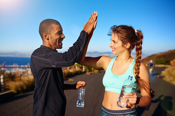 High five, man and woman on mountain for exercise, teamwork and confidence in fitness training together. Smile, nature and personal trainer with athlete, celebration and success in outdoor workout