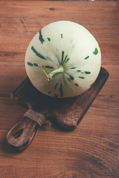 Dino melon, white with green stripes, small size, on the table, close-up, no people,